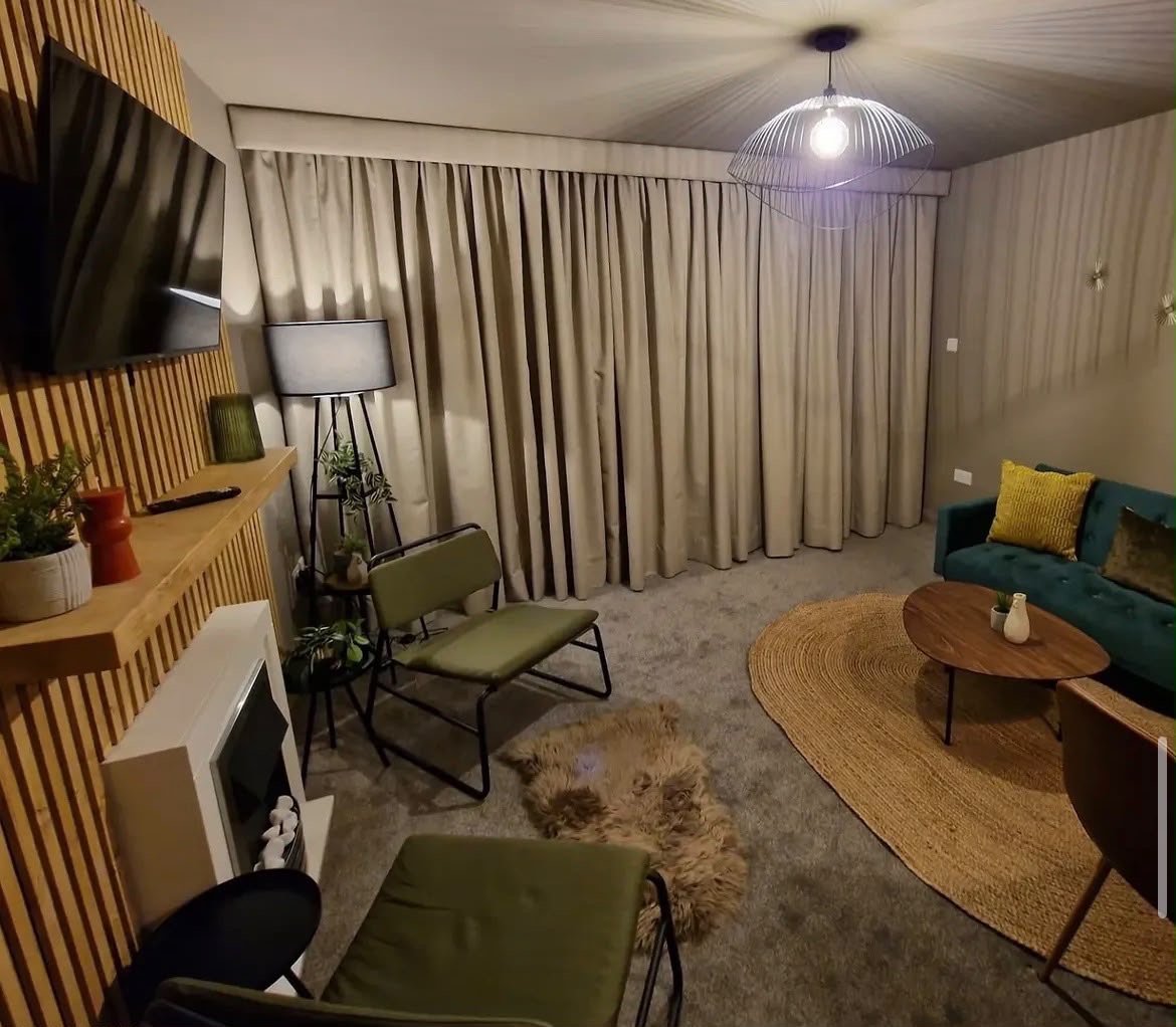 Living room with wood slat feature wall and teal sofa, decorated by English Rose